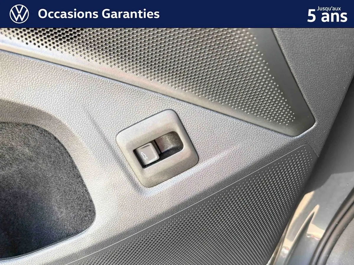 Détail du bouton d'ouverture électrique du coffre sur la porte arrière droite d'un Volkswagen Tiguan gris 2025.