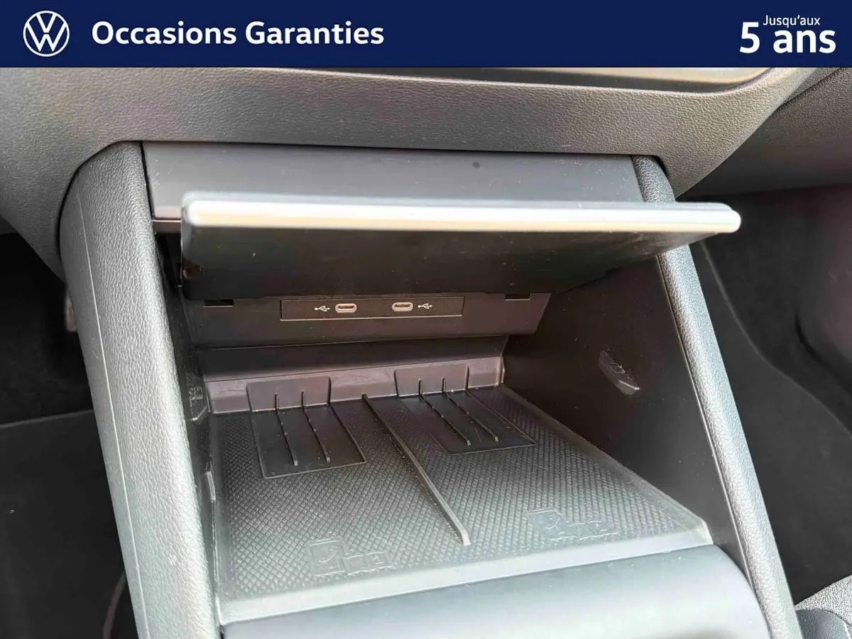 Gros plan sur la console centrale du Volkswagen Tiguan gris, montrant les ports USB-C et le compartiment de rangement ouvert.