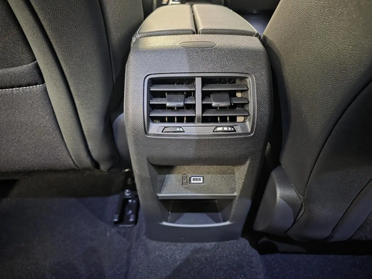 Vue rapprochée de la console centrale arrière noire de l’Opel Astra Hybrid 2024 avec bouches d’aération et port USB.