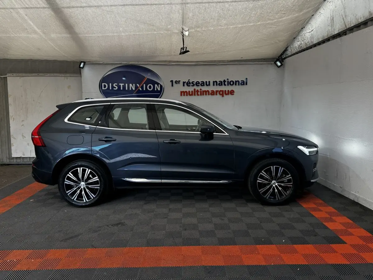 Vue de profil droit d'un Volvo XC60 bleu hybride rechargeable, avec jantes alliage et feux arrière distinctifs en forme de L.