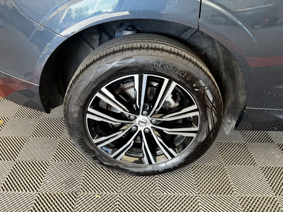 Gros plan sur la roue avant gauche du Volvo XC60 bleu, mettant en valeur la jante alliage noire et argentée.