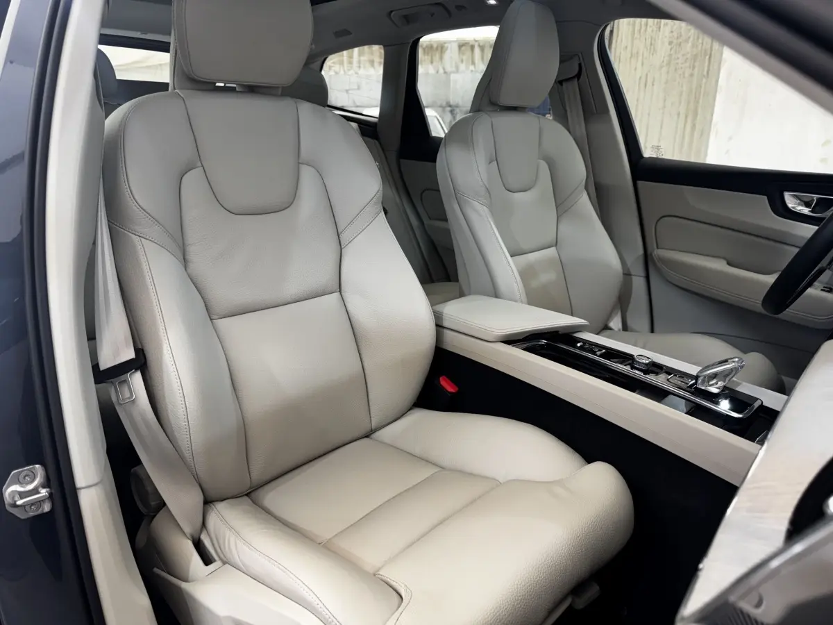 Vue intérieure côté conducteur du Volvo XC60 bleu, sièges avant en cuir beige avec console centrale élégante.