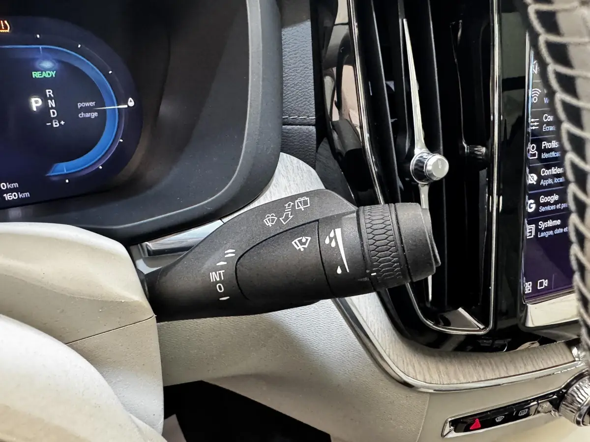 Gros plan sur la manette d’essuie-glace côté gauche du tableau de bord du Volvo XC60 bleu hybride rechargeable.