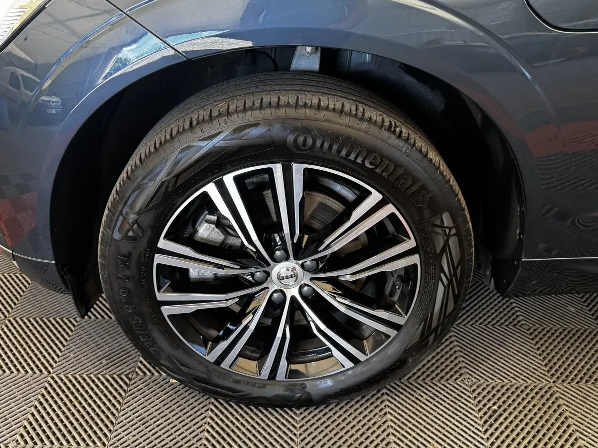 Gros plan sur la roue avant droite d’un Volvo XC60 bleu, jante alliage noir et argent avec pneu Continental.