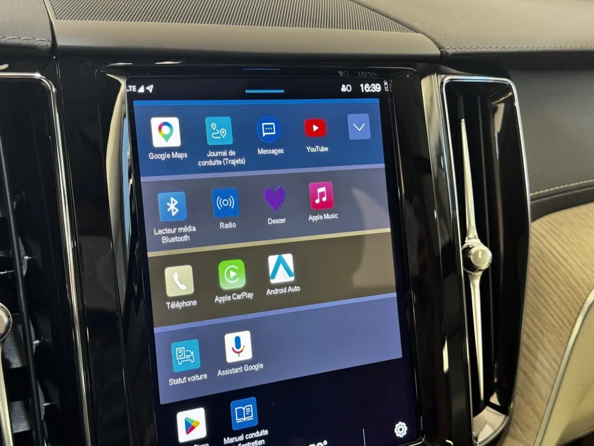 Écran tactile central du tableau de bord du Volvo XC60 bleu, affichant les applications multimédia et navigation.