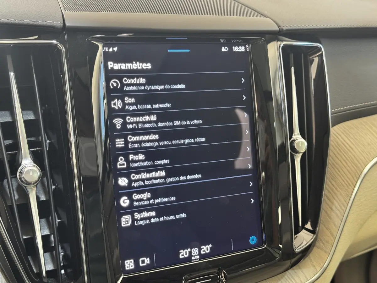 Écran tactile central affichant les paramètres dans l’habitacle clair d’un Volvo XC60 bleu hybride rechargeable.