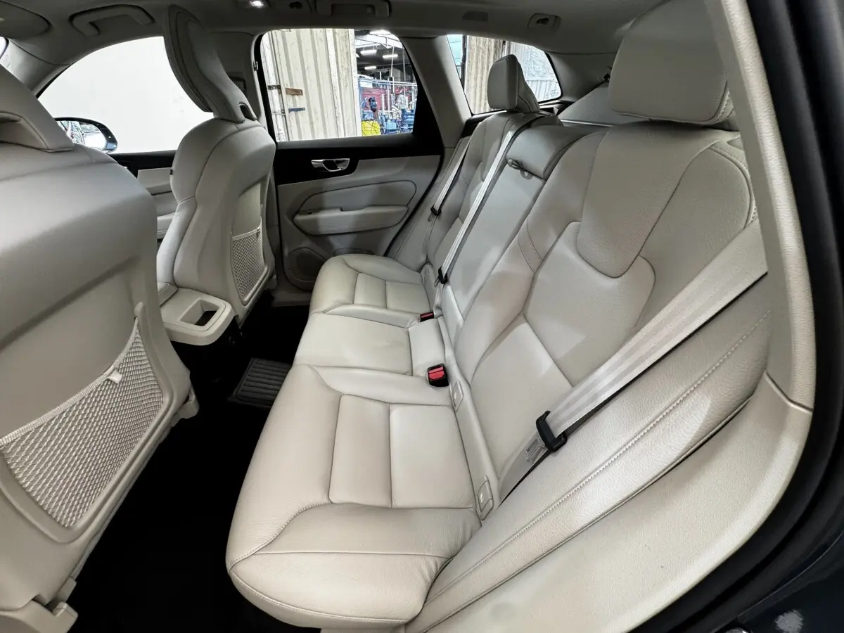 Vue intérieure côté droit des sièges arrière en cuir beige clair du Volvo XC60 bleu, avec ceintures de sécurité visibles.