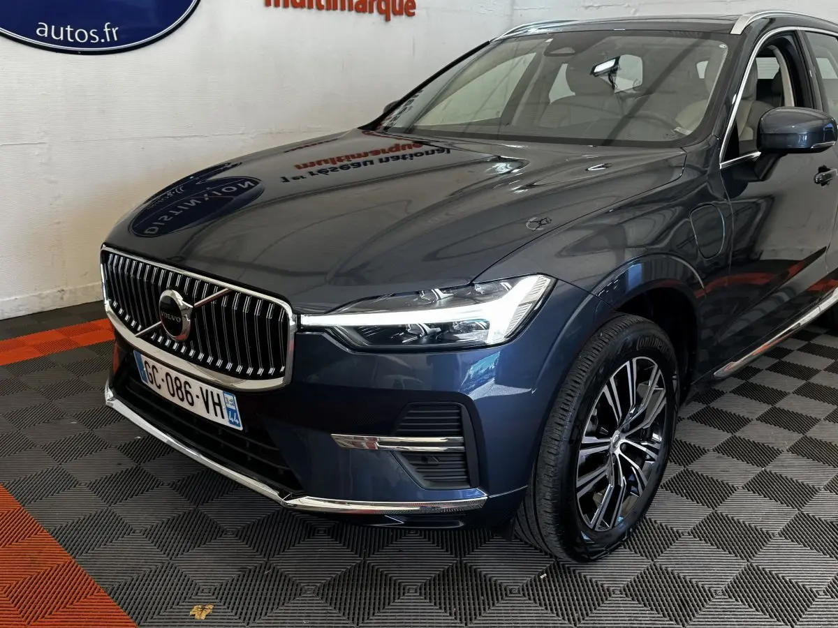 Vue 3/4 avant droit d’un Volvo XC60 bleu avec calandre chromée et jantes alliage noires.