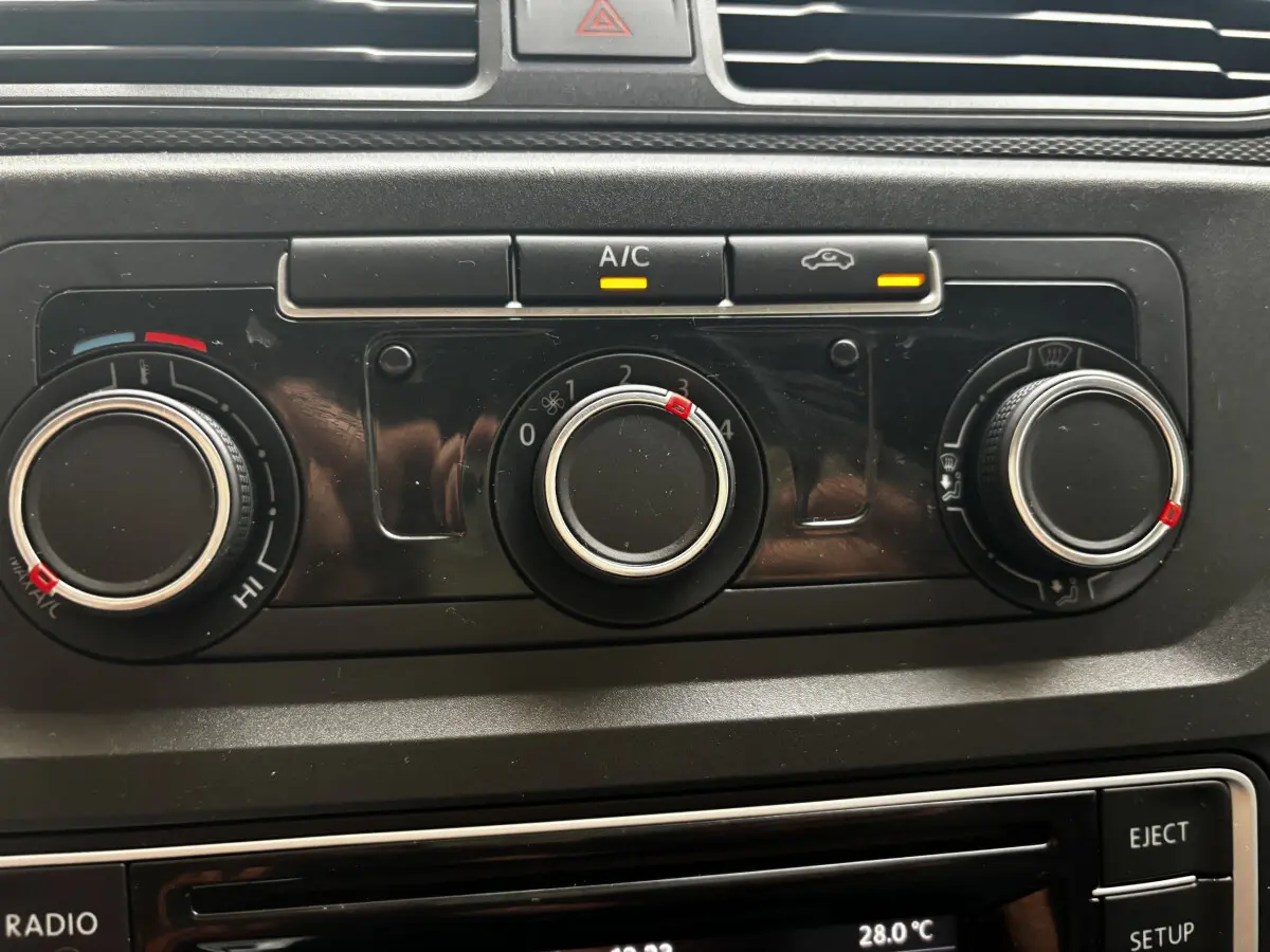 Gros plan sur les commandes de climatisation du Volkswagen Caddy gris foncé, avec boutons rotatifs et voyants A/C allumés.