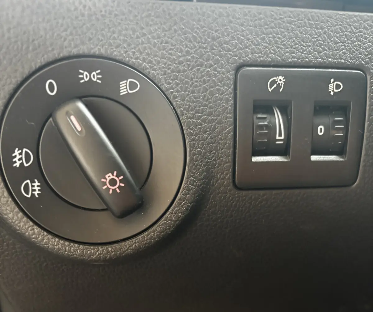 Gros plan sur les commandes d'éclairage et réglage des phares du Volkswagen Caddy gris foncé de 2019.