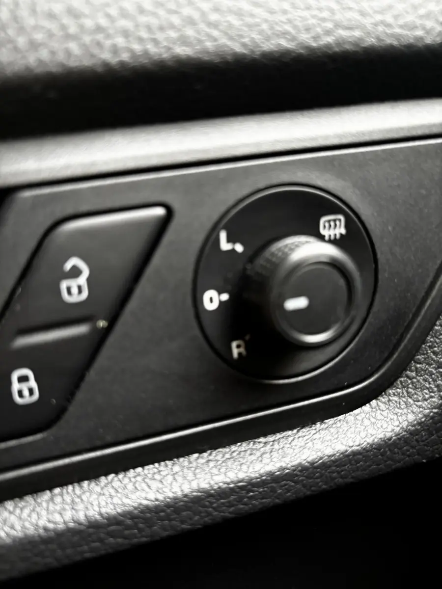 Gros plan sur les commandes de réglage des rétroviseurs et verrouillage des portes du Volkswagen Caddy gris foncé 2019.