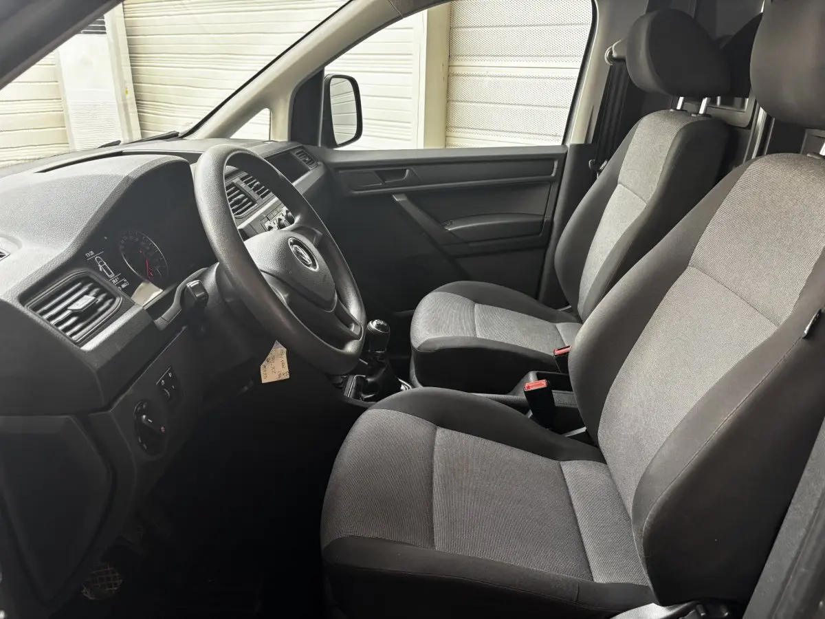 Intérieur avant du Volkswagen Caddy 2019 gris foncé, vue côté conducteur montrant sièges et tableau de bord.