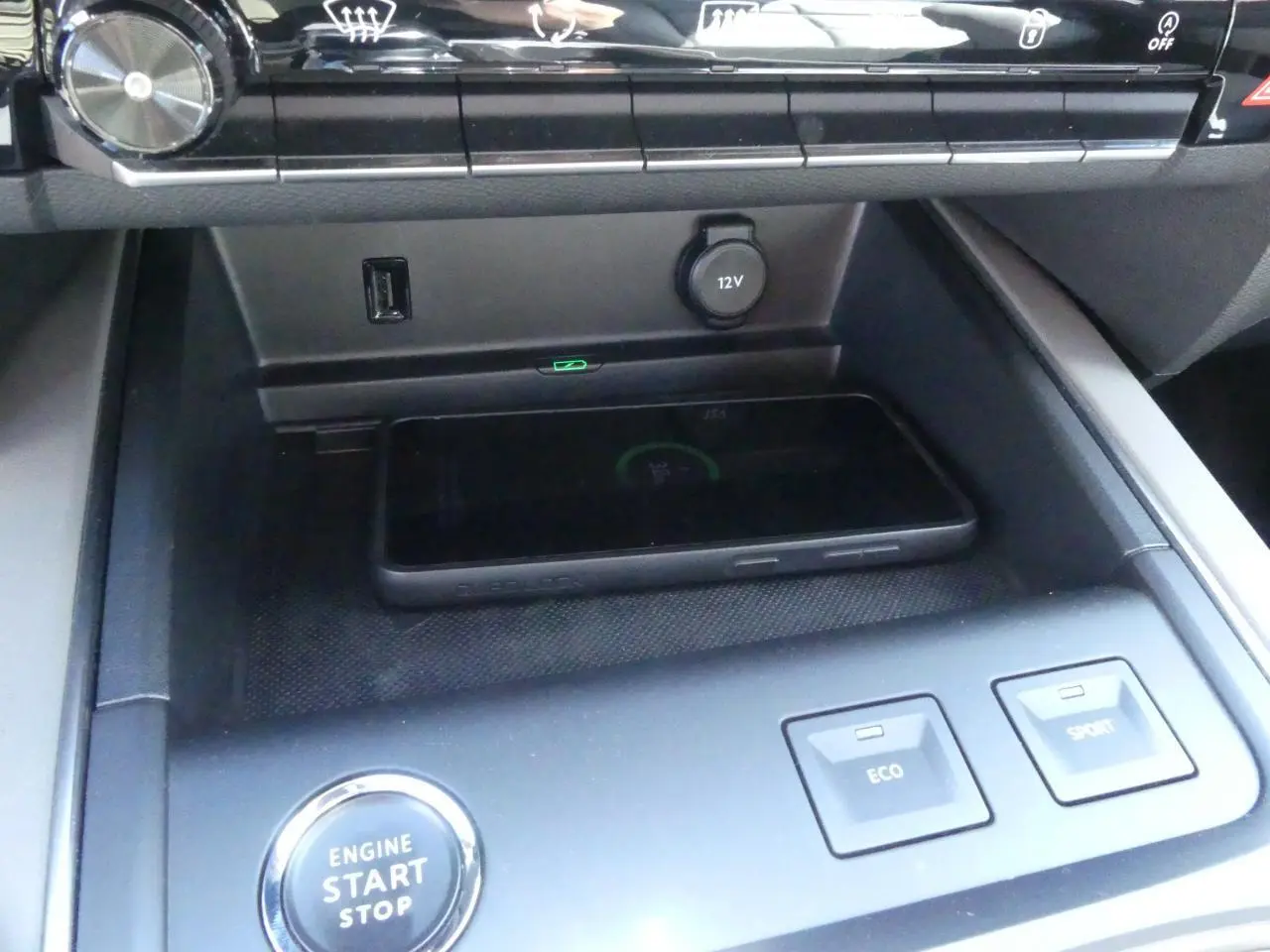 Gros plan sur la console centrale du Citroën C5 Aircross noir avec bouton start/stop, chargeur sans fil et commandes Eco/Sport.