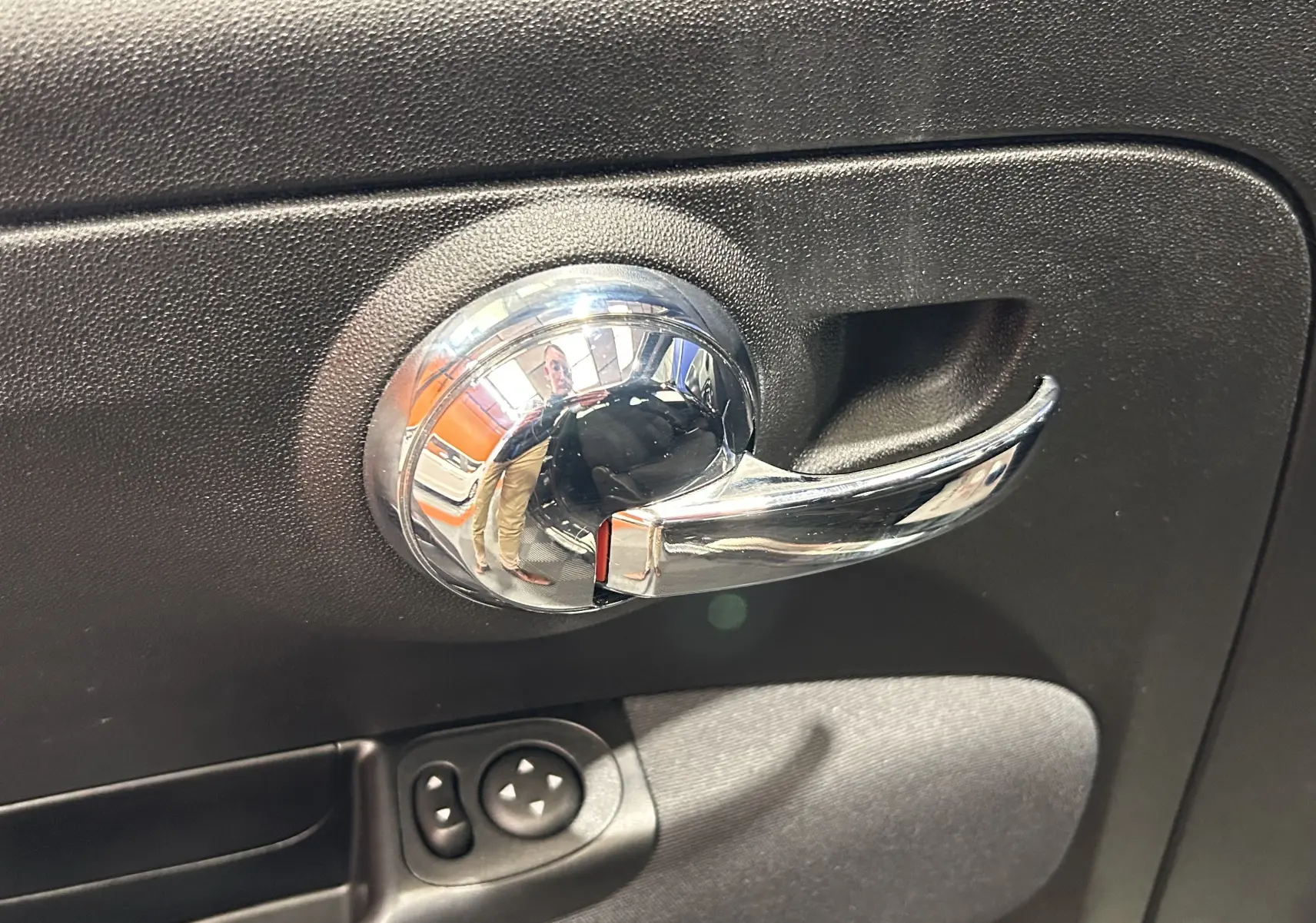 Poignée de porte intérieure chromée sur panneau noir, avec commandes électriques des rétroviseurs, Fiat 500 2023.