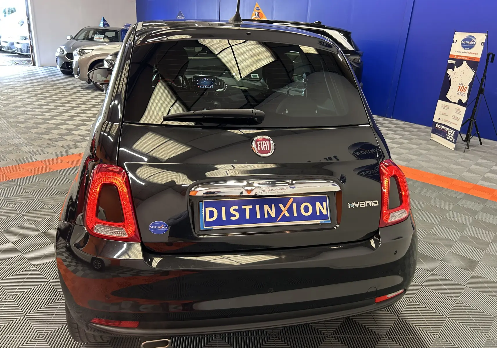 Vue arrière d'une Fiat 500 noire hybride 2023, avec feux LED et logo Distinxion sur plaque d'immatriculation.