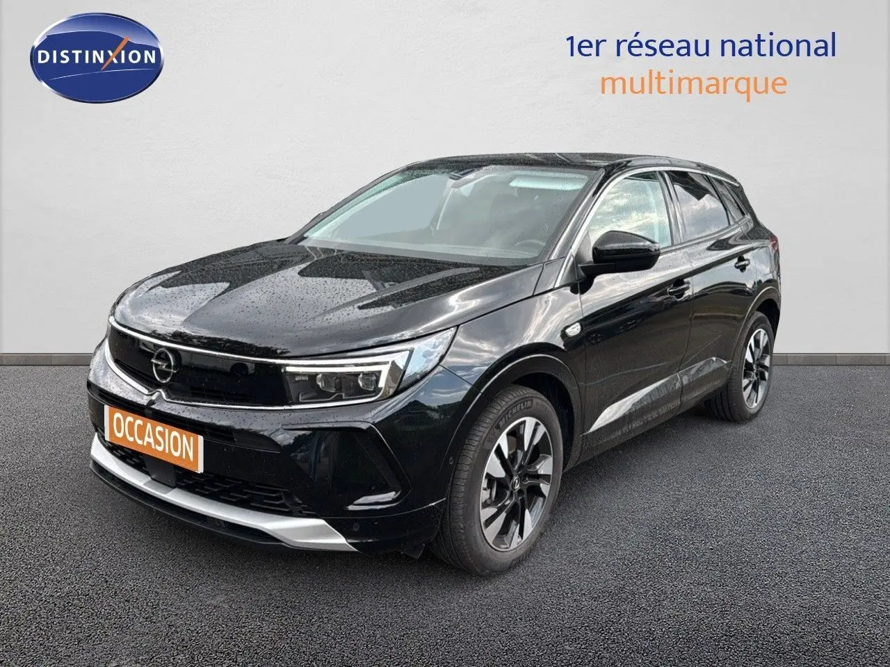 Opel Grandland 2024 noir en 3/4 avant droit, avec jantes bi-ton et calandre moderne sous la pluie.