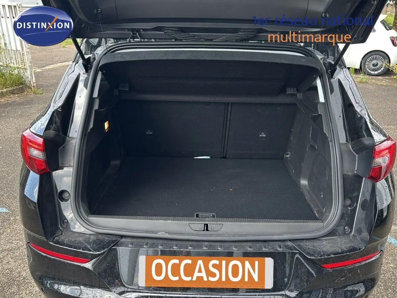 Coffre ouvert en vue arrière d’un Opel Grandland noir 2024 hybride rechargeable, montrant l’espace de chargement vide.