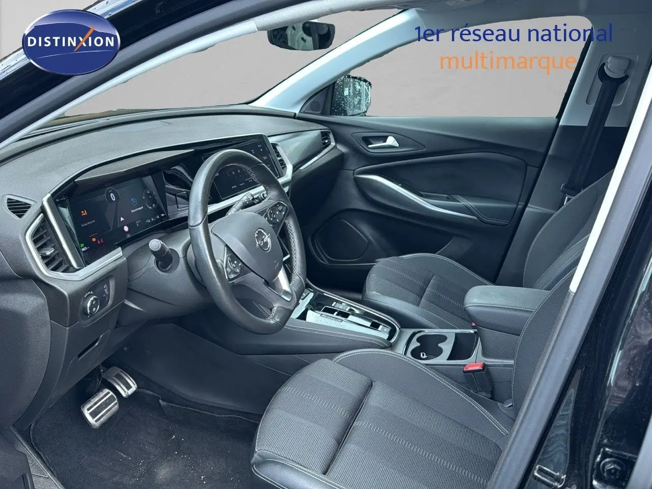 Intérieur avant droit de l’Opel Grandland noir 2024, montrant tableau de bord numérique et sièges tissu noirs.