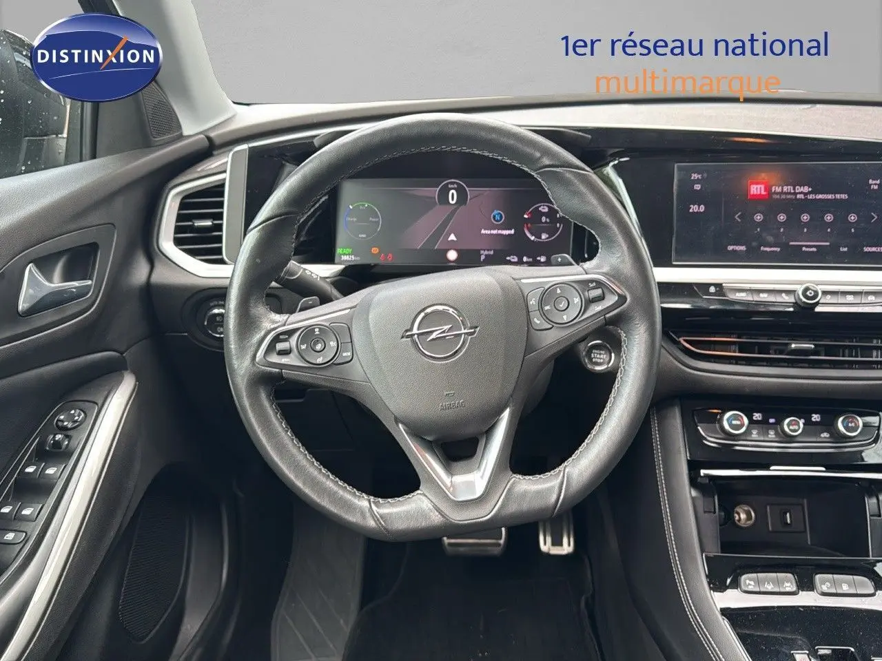 Vue intérieure centrée sur le volant cuir noir d'un Opel Grandland 2024 avec tableau de bord numérique et console moderne.