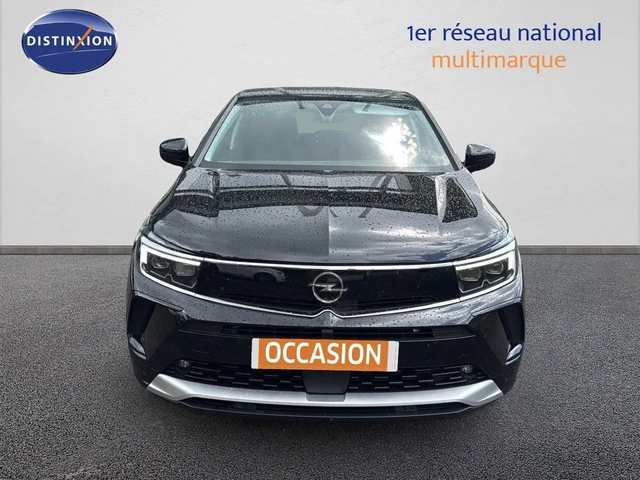 Vue avant d’un Opel Grandland noir 2024 hybride rechargeable avec calandre noire et détails argentés sous la pluie.