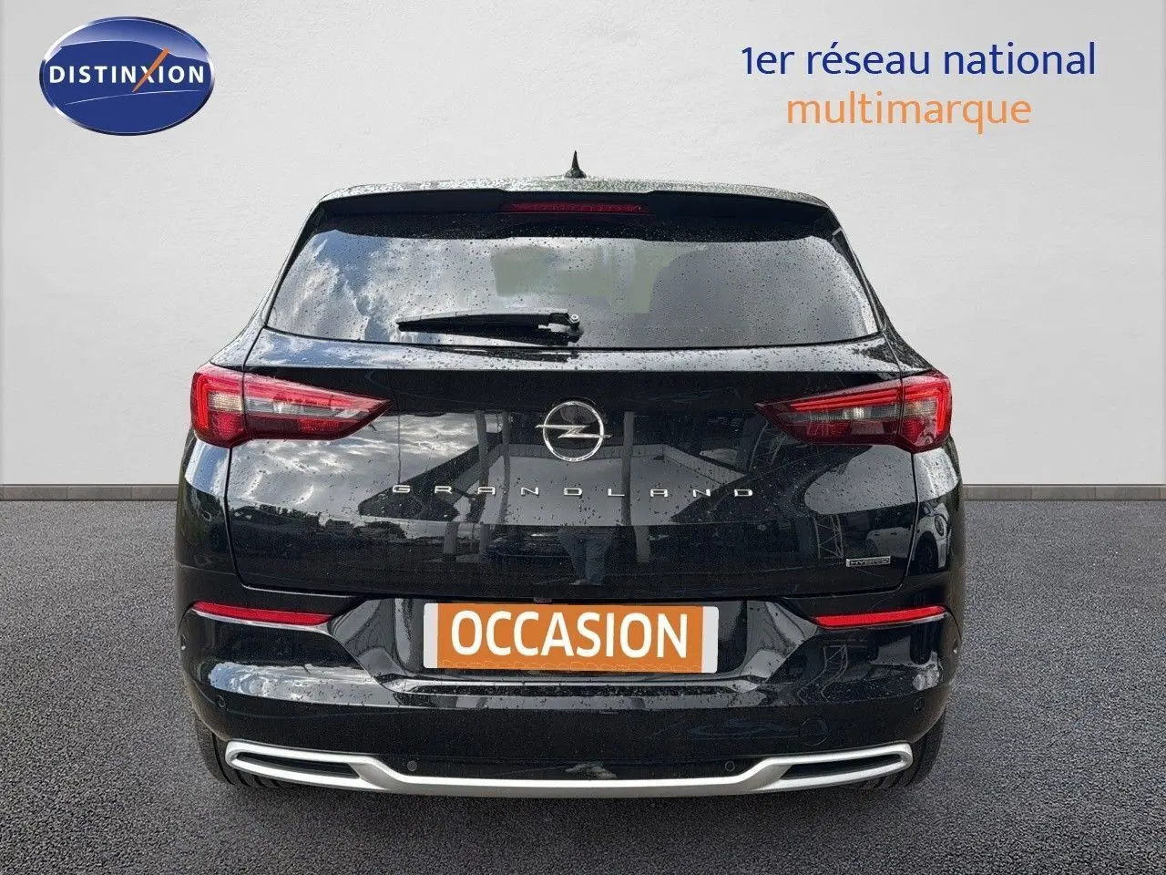 Vue arrière d'un Opel Grandland noir 2024 avec feux LED et logo distinctif sur fond gris.