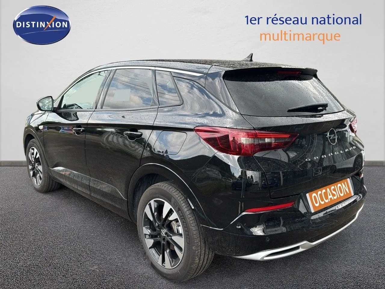 Vue 3/4 arrière droite d'un Opel Grandland noir 2024 hybride rechargeable avec jantes bi-ton et feux LED distinctifs.