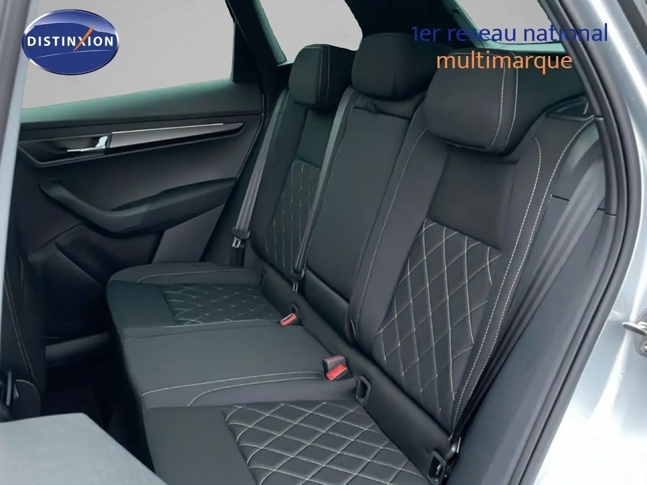 Vue intérieure sur la banquette arrière en cuir noir avec surpiqûres, porte ouverte côté droit du Skoda Karoq gris argent 2025.