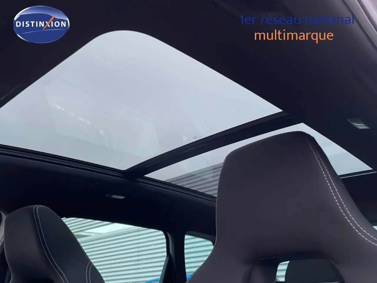 Toit panoramique ouvert vu de l'intérieur sur les sièges noirs avec surpiqûres blanches d'un Skoda Karoq gris argent 2025.