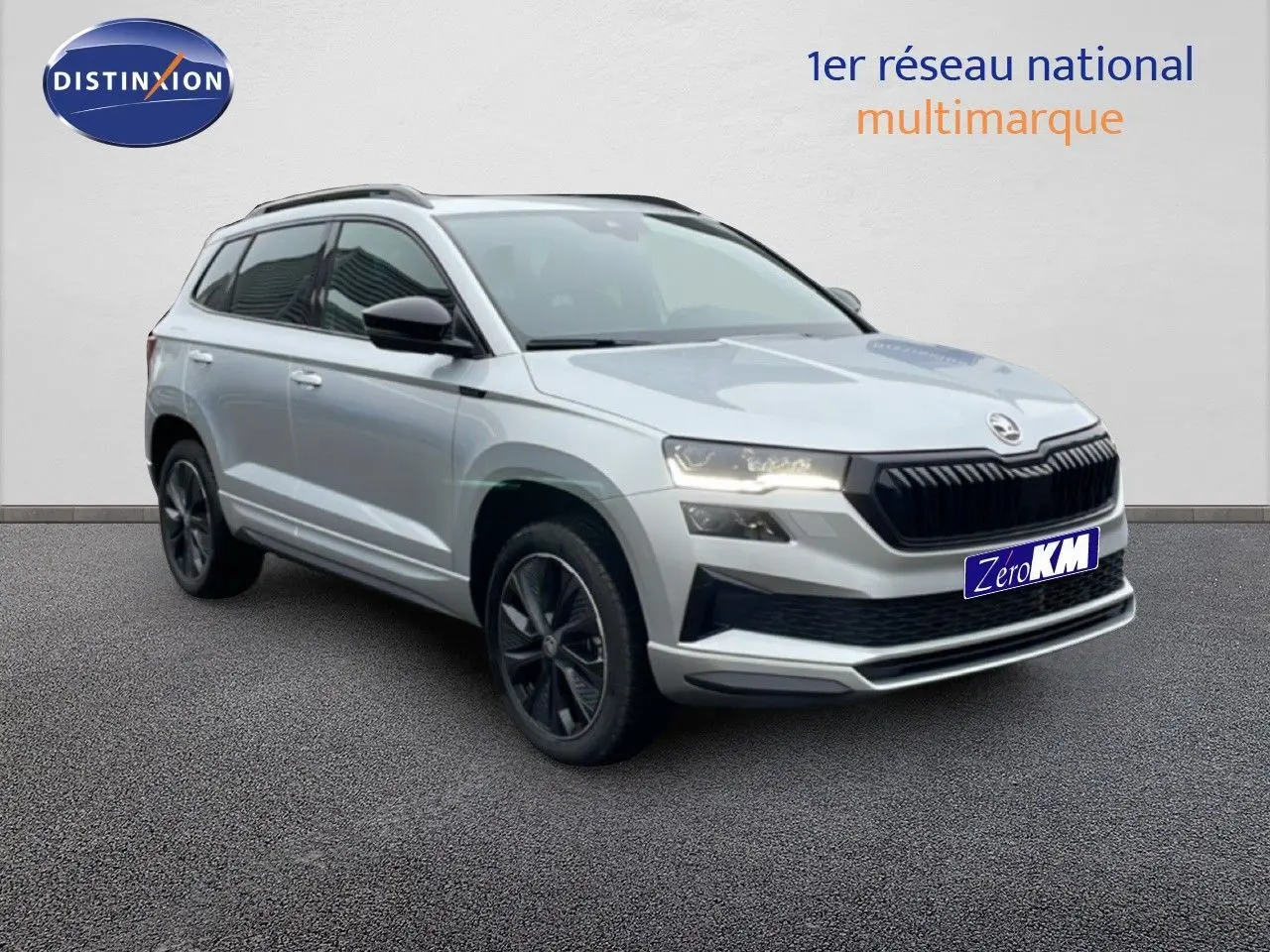 Vue 3/4 avant d’un Skoda Karoq gris argent métallisé 2025 avec jantes noires et calandre noire sportive.