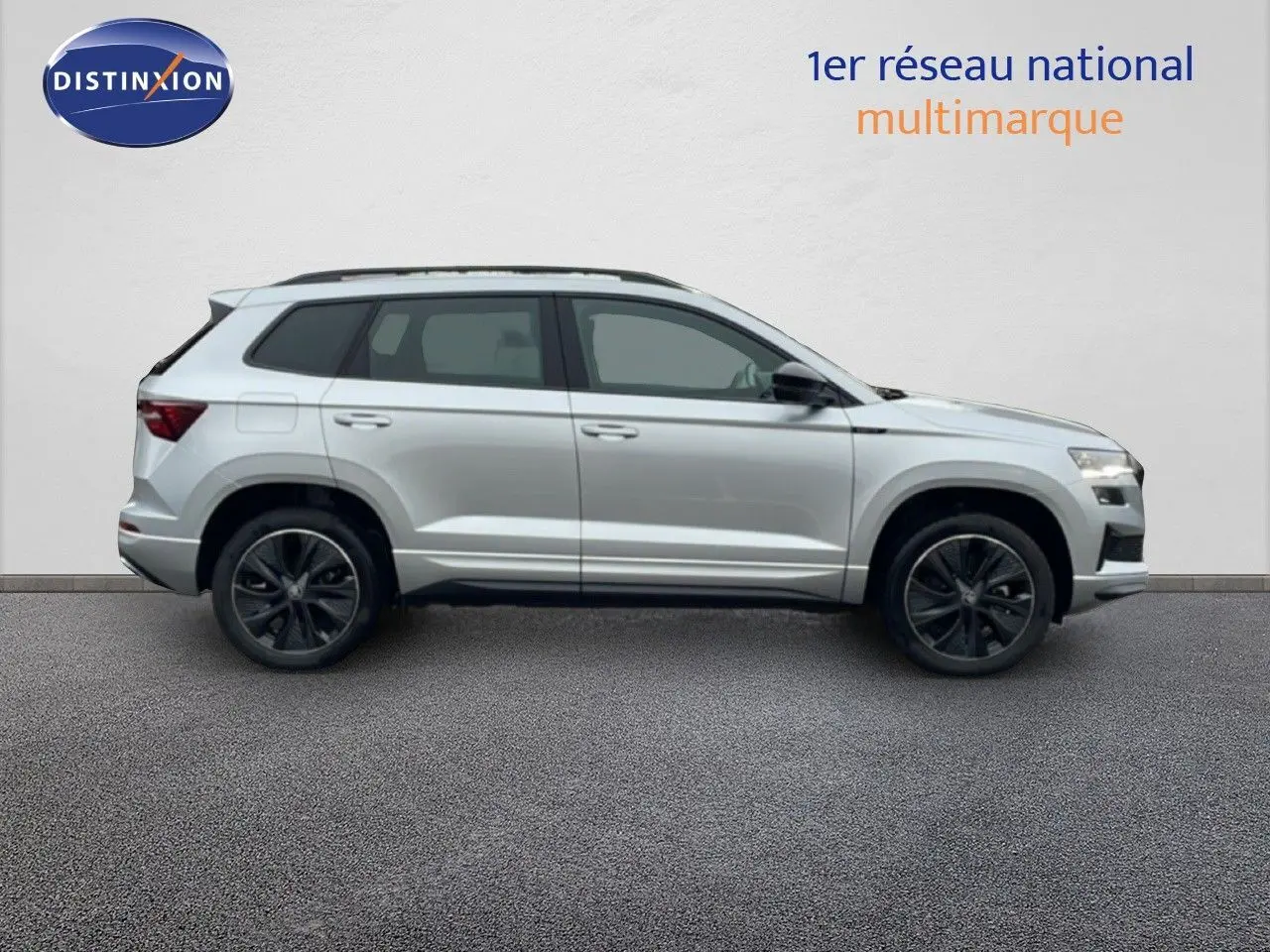 Vue de profil côté gauche d’un Skoda Karoq gris argent métallisé avec jantes noires et toit ouvrant.