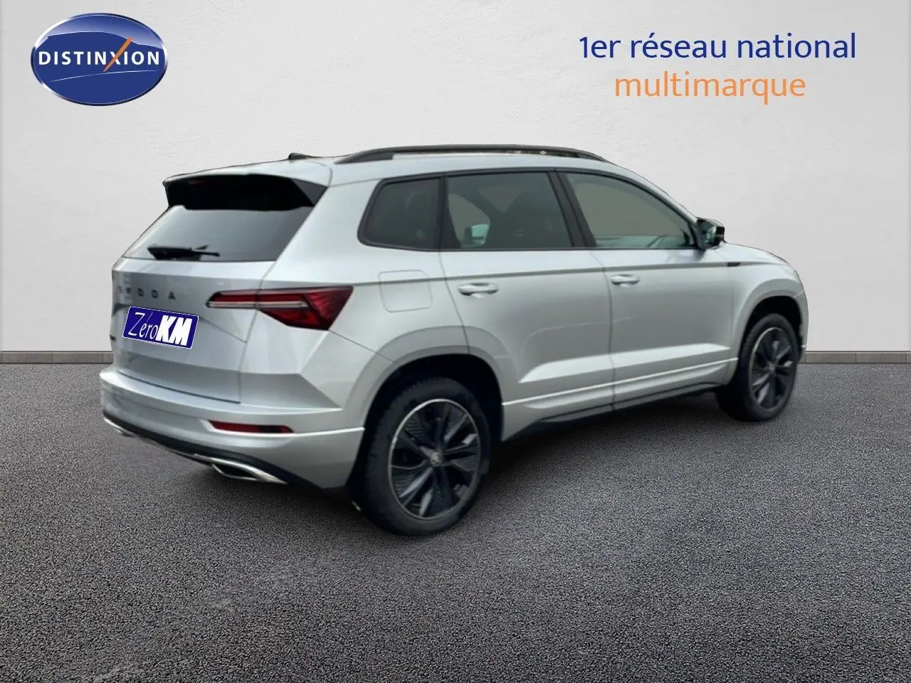 Vue 3/4 arrière droite d'un Skoda Karoq gris argent métallisé avec jantes noires et toit ouvrant.
