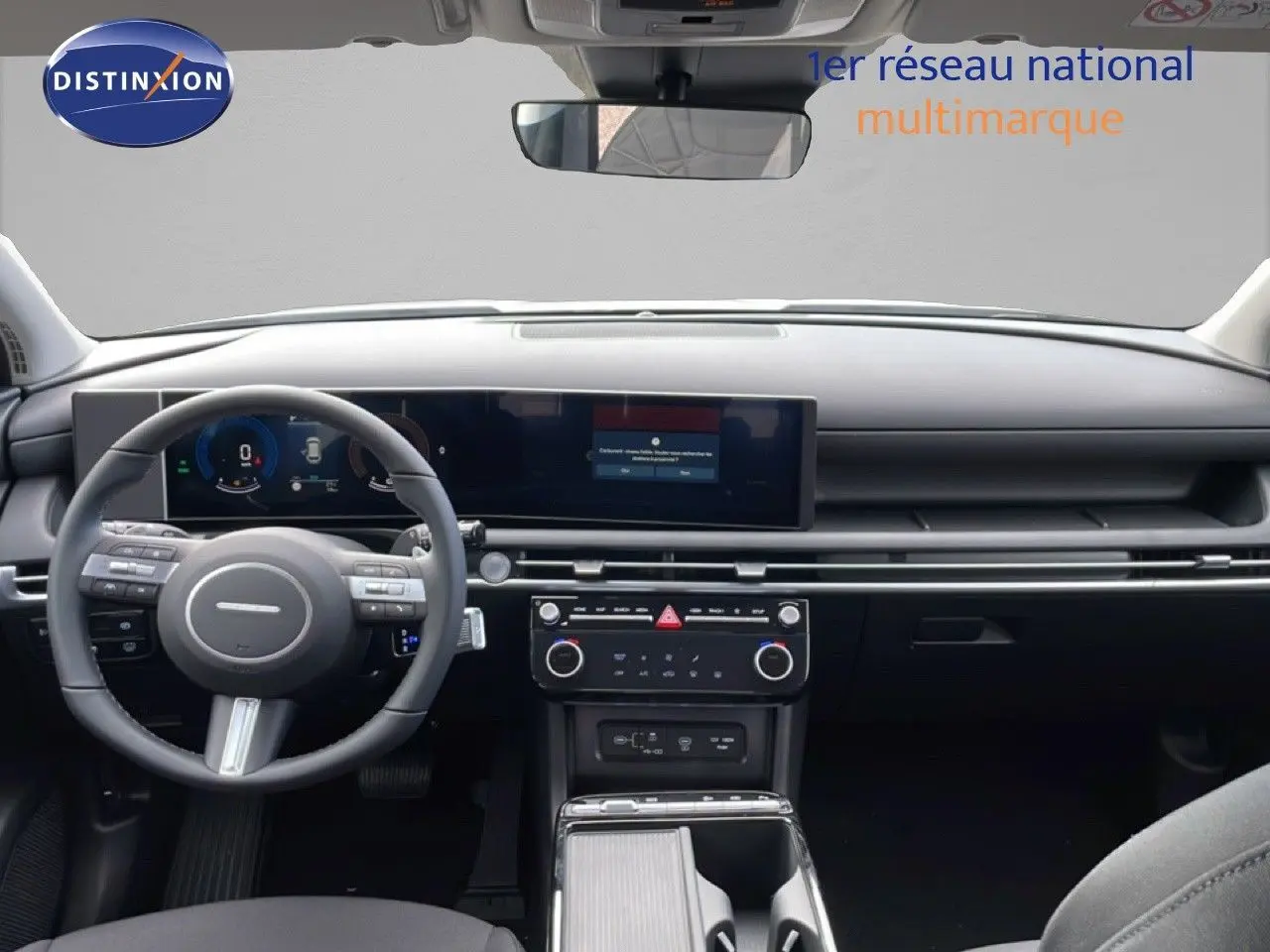 Vue intérieure avant du Hyundai Tucson blanc Atlas 2026, tableau de bord numérique et volant multifonction noir.