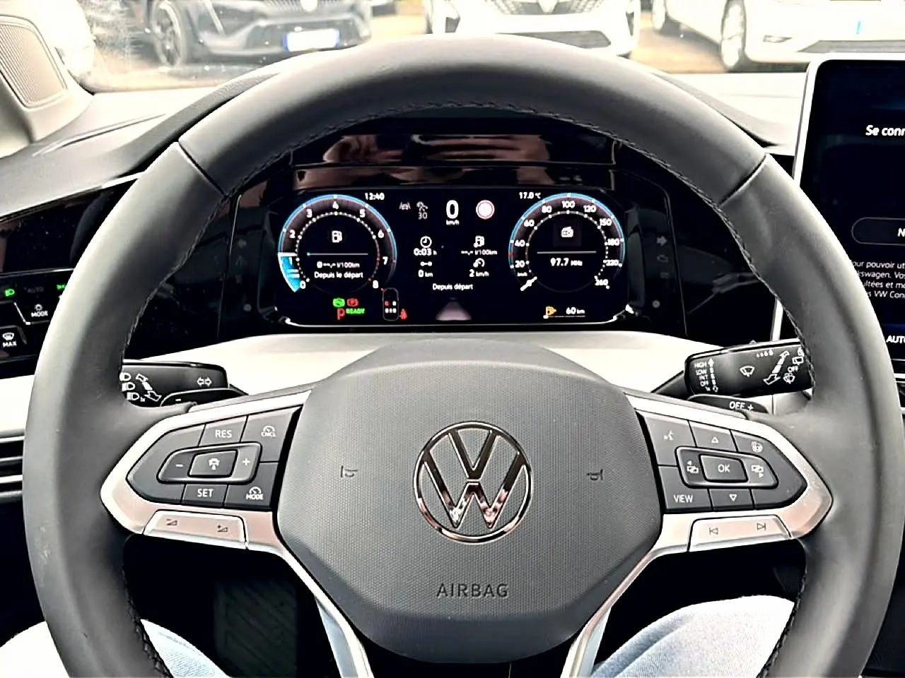 Vue rapprochée du volant noir de la Volkswagen Golf 2026 avec tableau de bord digital et commandes intégrées.