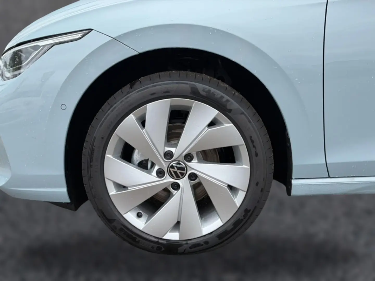 Gros plan sur la roue avant gauche et partie de l’aile d’une Volkswagen Golf bleu glacier avec jante alu 17 pouces.