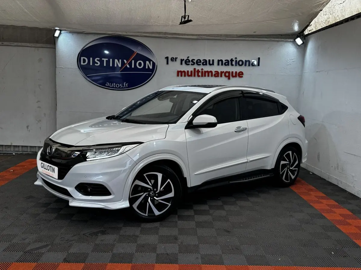 Honda HR-V blanc vue 3/4 avant droit, avec jantes noires et toit noir dans un showroom intérieur.