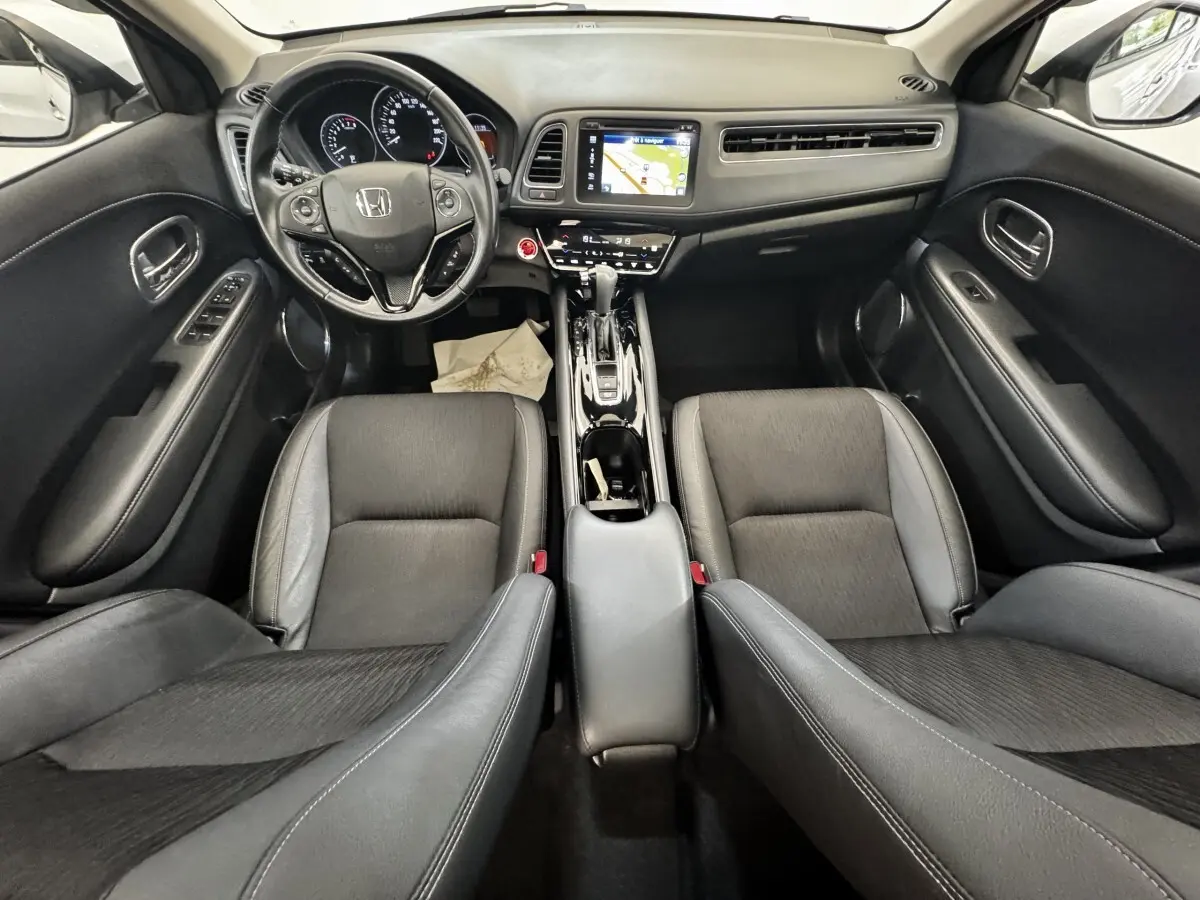 Vue intérieure frontale du Honda HR-V 1.5 i-VTEC 130 Exclusive, tableau de bord avec écran tactile et volant multifonctions noir.