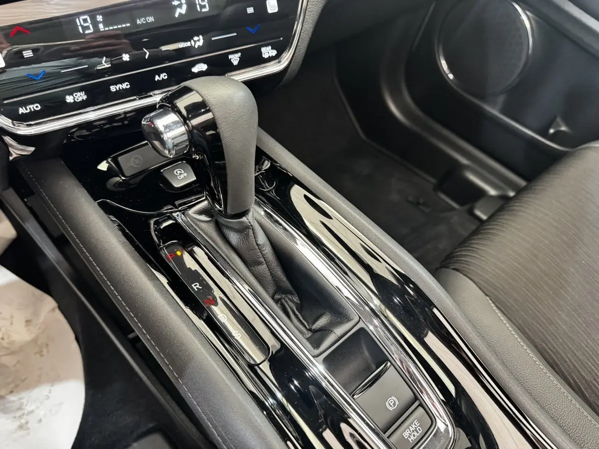 Gros plan sur la console centrale noire brillante du Honda HR-V 1.5 i-VTEC 130, levier de vitesse et frein électrique visibles.