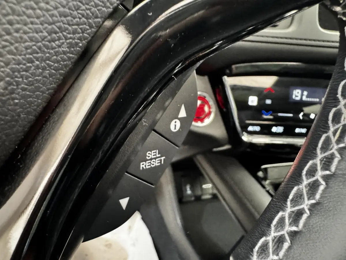 Gros plan sur le volant cuir noir avec surpiqûres blanches du Honda HR-V 1.5 i-VTEC 130, tableau de bord digital en arrière-plan.