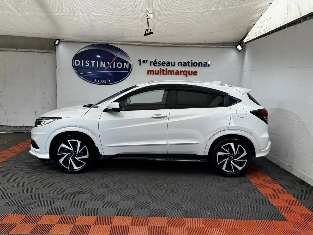 Vue de profil côté gauche d'un Honda HR-V blanc 2019 avec jantes alliage noires et toit spoiler.