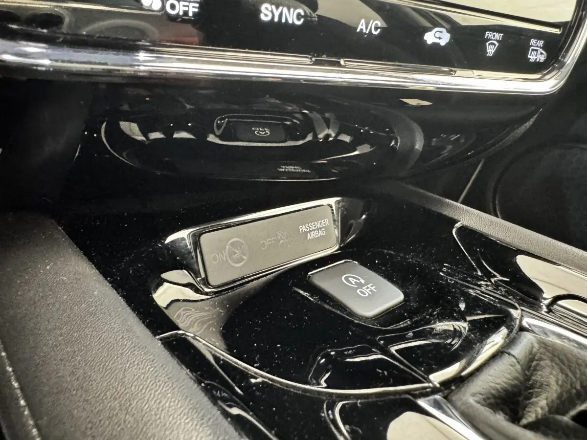 Gros plan sur la console centrale noire brillante du Honda HR-V 2019, avec bouton arrêt auto start-stop et indicateur airbag passager.