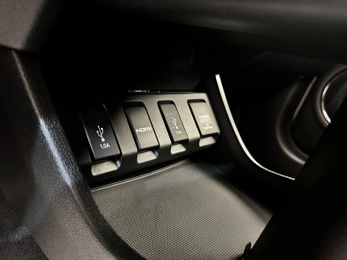 Gros plan sur les prises USB, HDMI et prise 12V noires dans l'habitacle du Honda HR-V 1.5 i-VTEC blanc.