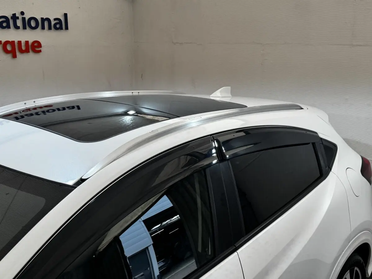 Vue rapprochée du toit ouvrant et des vitres teintées côté gauche d’un Honda HR-V blanc avec rails de toit chromés.
