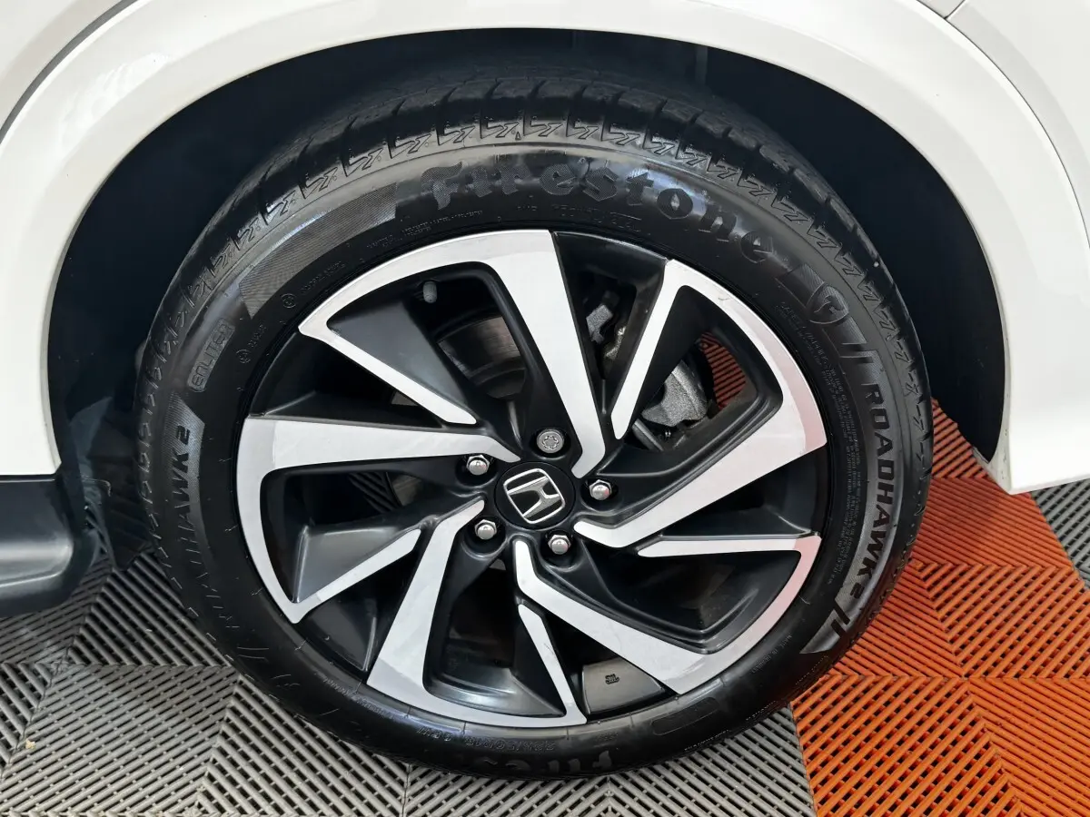 Gros plan sur la roue avant droite d’un Honda HR-V blanc, avec jante alliage noire et argentée distinctive.