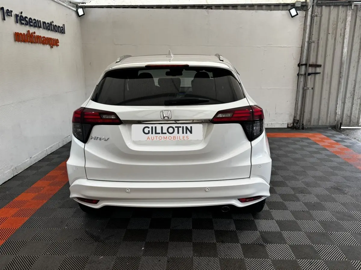 Vue arrière d'un Honda HR-V blanc 2019 avec spoiler de toit et feux arrière LED dans un garage.