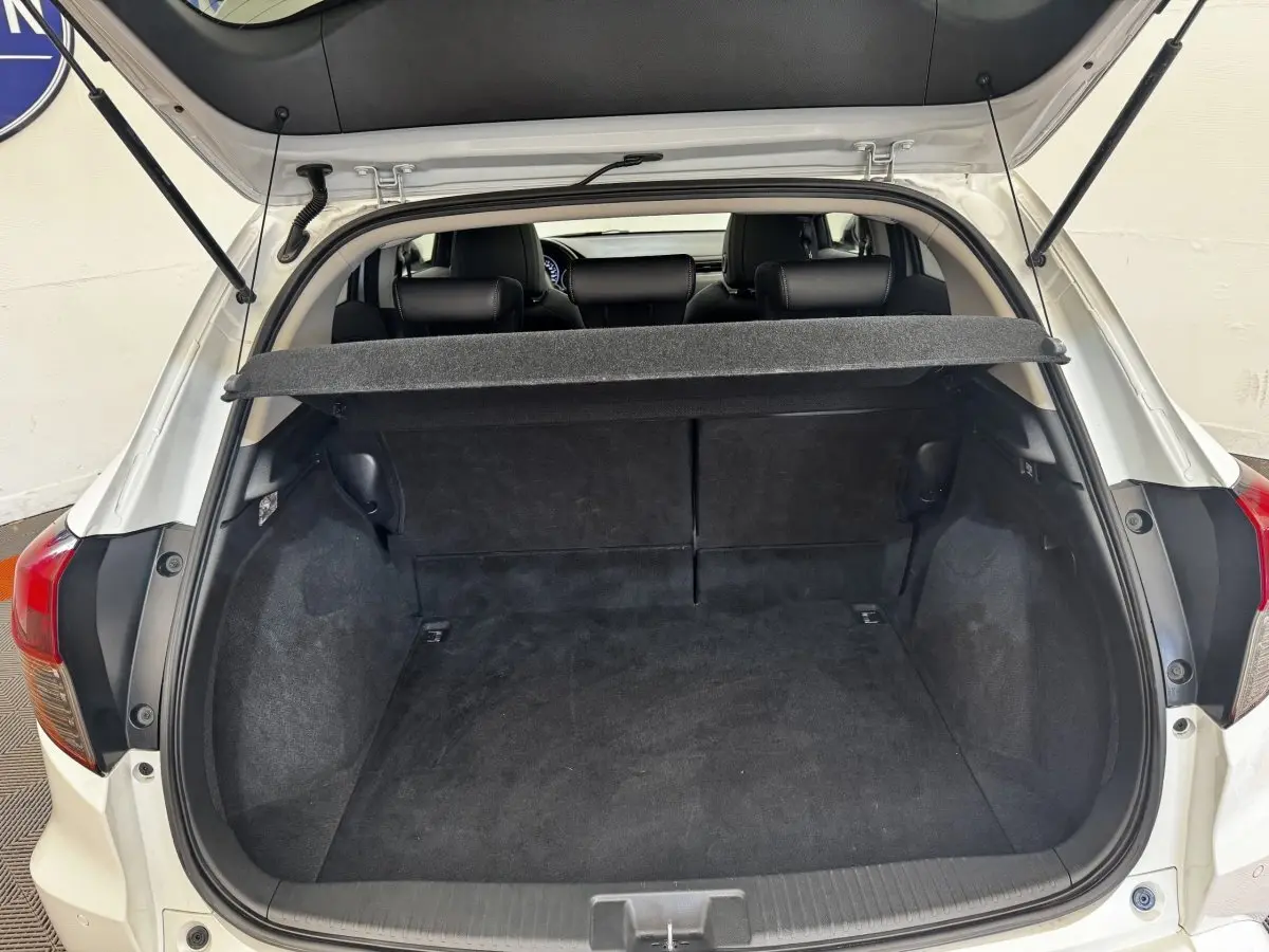 Vue arrière ouverte du coffre noir d'un Honda HR-V blanc 2019, avec tablette cache-bagages relevée.