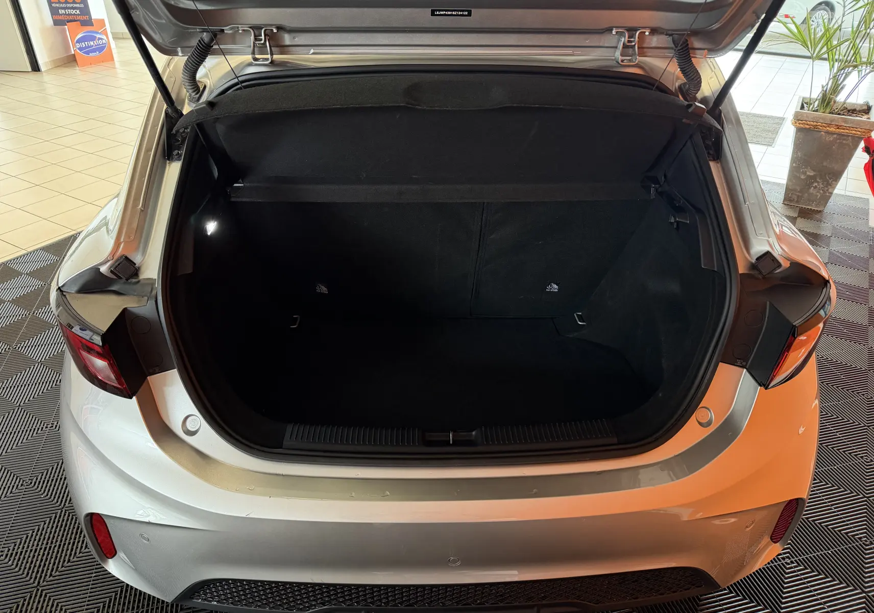 Coffre ouvert vu de l'arrière d'une MG3 1.5 L Hybrid+ cosmic silver, montrant l'espace de chargement vide.
