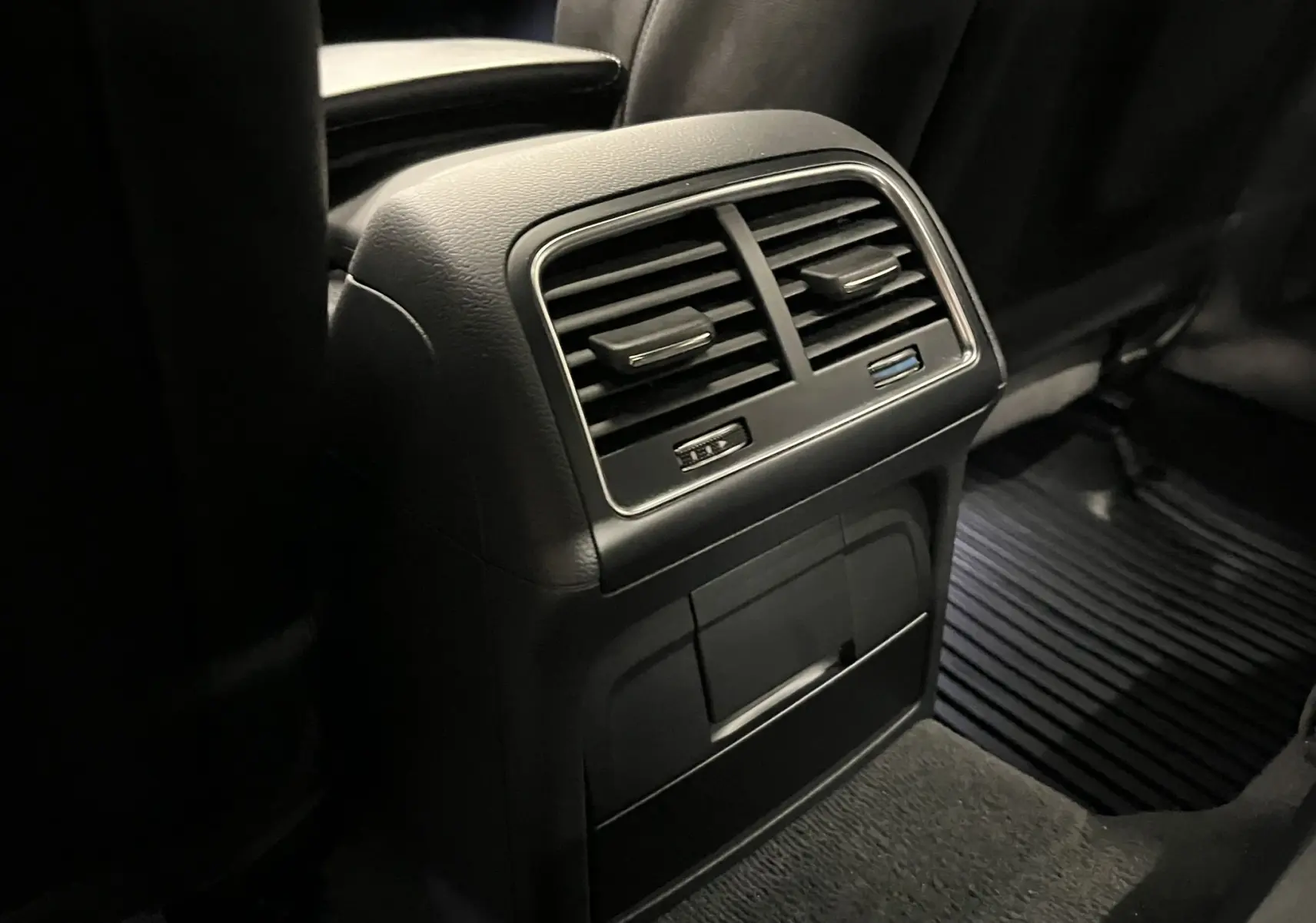 Vue rapprochée des aérateurs arrière noirs et des prises USB dans l’habitacle sombre de l’Audi A5 Sportback blanche.