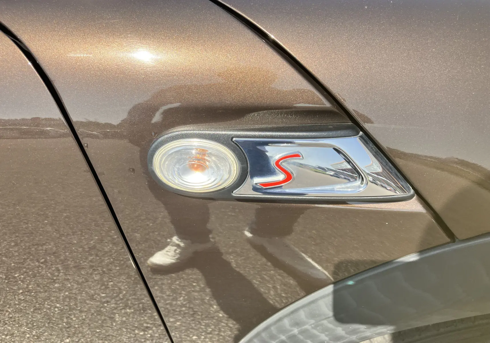 Gros plan sur le clignotant latéral avec logo rouge "S" sur une MINI Cooper S R56 marron métallisé.