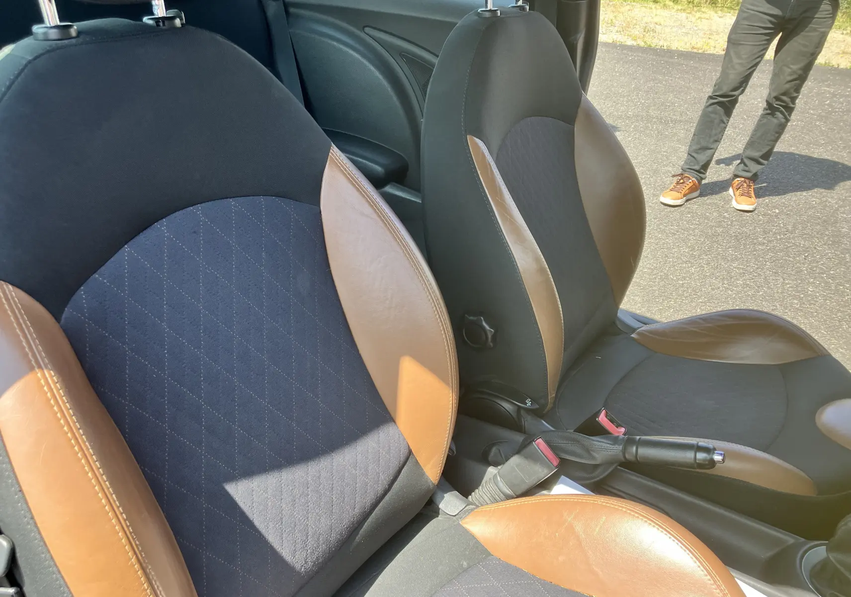 Gros plan sur les sièges avant bicolores noir et marron de la MINI Cooper S R56, avec intérieur et frein à main visibles.