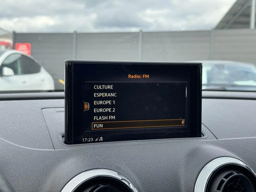 Écran central du système multimédia de l'Audi A3 Cabriolet 2019 affichant les stations radio FM, intérieur gris.